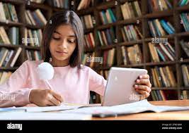 La colegiala latina concentrada viendo vídeo de aprendizaje en línea en  casa en la tableta Fotografía de stock - Alamy