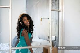 The loose curly hairstyles are always quite popular since they are romantic and luscious. Black Teenage Girl With Curly Hair Smiling Looking At Camera In Front Of A Mirror Listening To Music In Headphones Bedroom Dress Stock Photo 251671054