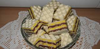 Un dulce, rapid si gustos, care nu necesita coacere si nu contine oua., 1 pachet foi de napolitane, 350g biscuit simpli (maruntiti cu robotul), 250g unt moale, 100g visinata, 30g esenta de rom (sau 1 fiola esenta), 200ml lapte, 200g nuci macinate, 300g zahar, 100g cacao. Prajitura Cu Foi De Napolitana Crema Fanta Si Crema De Nuca Gustoase Net