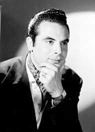 Fernando Casanova, actor, viste de traje y corbata, con cigarrillo  encendido en su mano derecha, retrato