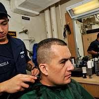 Ship's Serviceman 1st Class Ramon Kalaw cuts a Sailor's hair in the ship's  barber shop aboard the amphibious assault ship USS Bonhomme Richard (LHD  6).