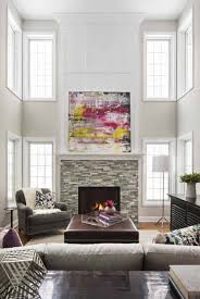 Gorgeous living room with light gray walls paint color, jonathan adler ventana 2 tier chandelier, marble fireplace surround, mirrored coffee table, oatmeal linen sofa & chair, khanjali ikat fabric pillows. 30 Exquisite Interior Spaces Showcasing The Color Greige