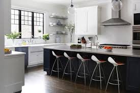Bright, open design informs this modern kitchen, centered on a large white island with an extended countertop for dining space.a set of carved wood bar stools act as a rustic counterpoint to the contemporary look of stainless steel appliances and cupboard doors. White Cabinets With Blue Kitchen Island Transitional Kitchen