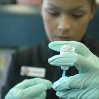 Hospital Corpsman 3rd Class Kyra Moses administers a vaccination shot to  Damage Controlman Fireman Joseph Allen i