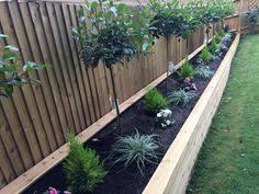 A Raised Wooden Flower Bed With Red Robin Trees Conifers Plants Diy Garden Fence Wooden Garden Edging Conifer Plants