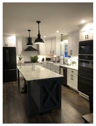 The clean white cabinets and classic white sink make the space feel large, but the butcher's block countertops and burnished silver drawer pulls give the whole look a rustic flair. Farmhouse Kitchen Black And White Kitchen Farmhouse Blackandwhitekitchenfarmhouse In 2021 Home Kitchens Black Appliances Kitchen Home Decor Kitchen