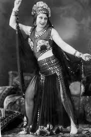 A rare photo of Badia Masabni in a dance costume adorned with quite a few coins. 1930s. It's a bit difficult to tell if she's wearing sandals. There is a strap visible