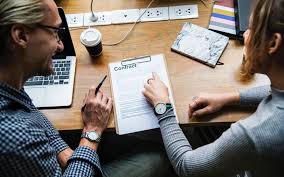 two people looking at a contract, one person is pointing at where to sign and the other is signing the contract