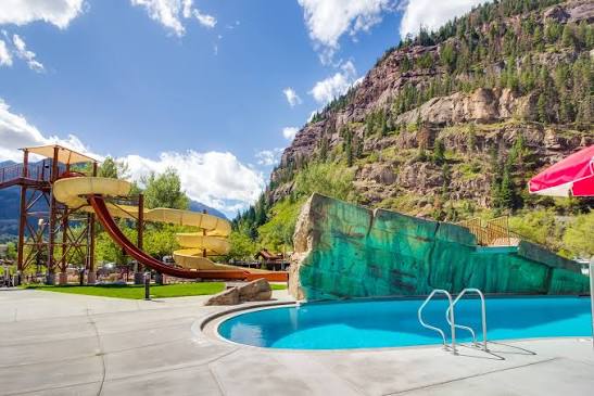 Swimmers in the Ouray Hot Springs Pool with snow covered canyon walls rising behind in winter