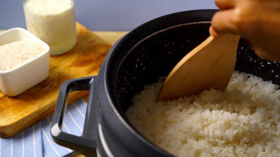 Hand gently fluffing cooked kabsa rice with a fork to separate grains without breaking them