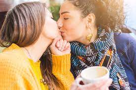 レズビアンのカップルがカフェでキスします。若い女性は、一緒にコーヒーを飲んでいるし、お互いに情熱的なキスを与えます。実質の人々  と率直な状況。同性愛および生活様式の概念。の写真素材・画像素材 Image 61639006