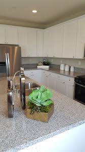 The floors in the kitchen must be made of materials that are easy to clean and maintain. White Speckled Grey And Black Granite White Cabinets Vinyl Plank Flooring Throughout Kitchen Remodel Idea Vinyl Flooring Vinyl Tile Flooring