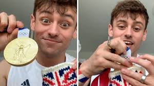 Tom daley shown in the stands with knitting needles and a handmade creation. 9 3awyvcrp6rdm