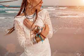 ビーチで白いロングドレスと銀の宝石を身に着けた自由奔放に生きるスタイルのモデル。彼女の髪は編まれており、彼女の腕にはたくさんのブレスレットがあります。の写真素材・画像素材  Image 201629842
