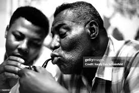 Guitarist Hubert Sumlin lights blues musician Howlin' Wolf's pipe as...  News Photo