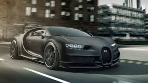 Matte black sports coupe parked beside gray cyclone fence. Bugatti Edition Chiron Noire Exclusive Special Model