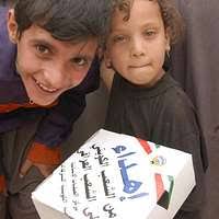 Iraqis share a laugh with a U.S. Army Specialist Michael Toro during an  effort to distribute food and water to Iraqi citizens in need