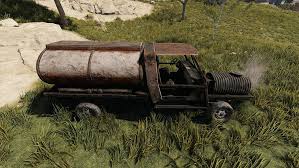 A rusty, derelict tanker truck with a large cylindrical tank on its bed is parked on a grassy hillside, representing a target for raiding in Rust