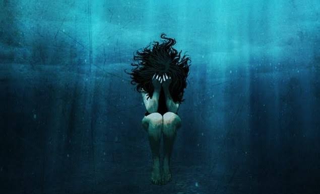 A person underwater, curled up and upset