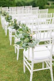 elegantly lined white wedding ceremony chairs accented by rustic italian greenery t outdoor wedding chairs wedding chair decorations pastel wedding decorations