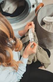 There's a pile of dirty laundry in the laundry basket. Woman Looking At The Tag On The Clothes Before Loading Stock Photo Crushpixel