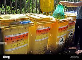 Berlin, Germany. 28th July, 2020. A woman disposes of her garbage  separately in the designated bins. About two thirds of the residual waste  in German households is waste that should be disposed