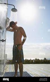 Teenage boy (16-17) standing under outdoor shower Stock Photo - Alamy