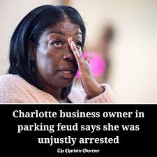 The dispute over parking between Charlotte business owners Robbie  McNair-Guzman and Jim Noble has escalated further, with McNair-Guzman being  arrested for what she says is a false accusation of communicating a threat