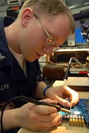 U.S. Navy Electronics Technician 3rd Class Christopher Ralph uses a  soldering iron to make repairs