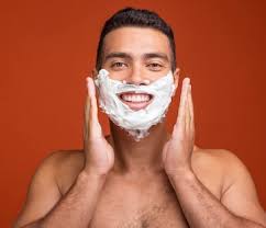 Vooraanzicht van smiley shirtless man met scheerschuim op zijn gezicht