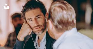 Dois homens sentados em uma mesa conversando um com o outro foto