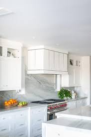 Ceiling height backsplashes, larger subway tiles, bold colors/patterned tiles or marble slabs? White And Silver Range Hood With Marble Slab Backsplash Transitional Kitchen