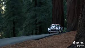 OpenAI 的 SORA 是很強，但這台車根本是變形金剛吧！😂, Prompt: A wide shot video of a rally car  driving through a redwood forest and showing up behind the trees , spraying  dirt into the air as it drifts around a sharp ...
