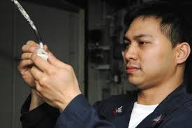 US Navy (USN) Electrician's Mate Second Class (EM2) Johnny Ang checks the  electrical contacts