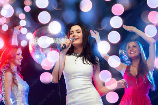 three smiling women dancing and singing karaoke Stock Photo | Adobe Stock