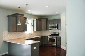 White and grey marble countertop retains the interest as well as conveys a lavish impression. Gray Cabinets With White Subway Tile Herringbone Backsplash Tiles Transitional Kitchen