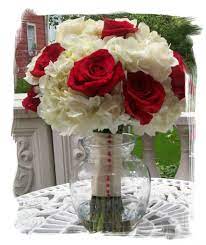 Florist composing bouquet with rose, hydrangea and chrysanthemums, while looking at laptop on desk on blurred background. Stefanie Possible Bridesmaid Bouquet Just A Little More Symmetrical Red Bouquet Wedding Hydrangea Bouquet Wedding Red Rose Bridal Bouquet