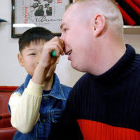 US Air Force (USAF) SENIOR AIRMAN (SRA) Anthony Paternoster, 8th  Comptroller Squadron, gets his nose tugged by Shim Yong, an orphan from Kae  Chong Orphanage during a Halloween Party sponsored by the
