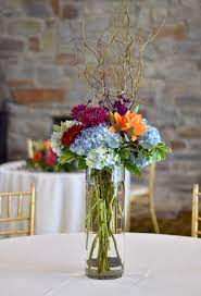 Colorful Tall Centerpiece Featuring Blue Hydrangea Orange Lilies Red Gerbera Dais Blue Wedding Centerpieces Wedding Table Flowers Blue Hydrangea Centerpieces