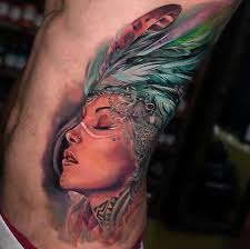 This is a heavily detailed tattoo of a native american woman wearing face marks or her tribe, a head piece and some feathers. Art Amazing Color Realism Rainbow Feathers Native