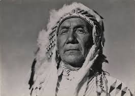 Yellow Kidney (left) and his father, Little Plume, inside a lodge, pipe  between them. (Library of Congress). By Edward S. Curtis-