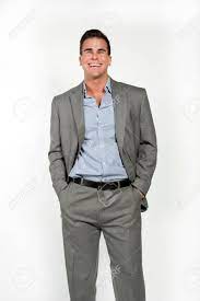 Chemise très légèrement bleu ciel. Athletique Et Attrayant Caucasien Male Vetu D Un Costume Gris Equipee Avec Un Bouton Bleu Bas Chemise Dans Un Cadre Sur Un Fond Blanc Posant Et En Regardant La Camera Et Souriant Studio