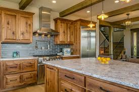 Rustic Kitchen With Exposed Beams Knotty Wood Cabinets And Blue Subway Tile Backsplash By Lake House Kitchen Rustic Kitchen Cabinets Stained Kitchen Cabinets