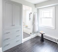 A curved built in linen cabinet is fitted with glass front cabinets flanked by white drawers adorned with polished nickel pulls and white overhead cabinets. Creative Ways To Incorporate Built In Cabinetry