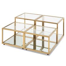 Legs are a metal chrome finish with dark brown wood trim, while the coffee table itself has a lower shelf that is made of frosted glass. Evans Glass Coffee Table Set 4 Brushed Gold Interiors Online