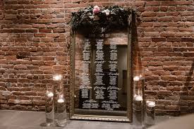 large mirror seating chart with floral hedge and candles