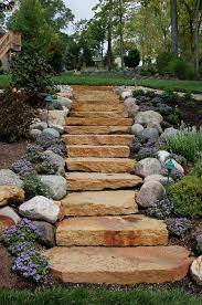 A large stone is used to span a constructed stream in this rock garden landscape. Rustic Buff Natural Steps Mccarty Mulch
