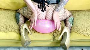 バルーンフェチ。美しさは風船を膨らませ、彼女の美しいお尻でそれに座っています。