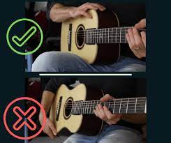 Wear the strap comfortably over your shoulder and adjust the height so you can easily hold the guitar with both hands. Lesson 1 How To Hold The Guitar Fingerstyle Guitar Lessons