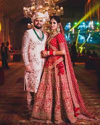 Photo Of Contrasting Bride And Groom Outfits In Red And White Couple Wedding Dress Wedding Outfits For Groom Indian Wedding Outfits
